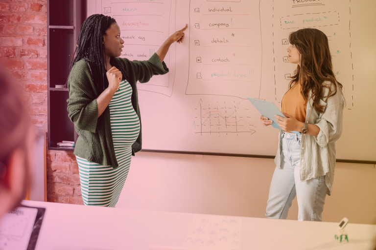 Pregnant employee giving a company presentation on a whiteboard